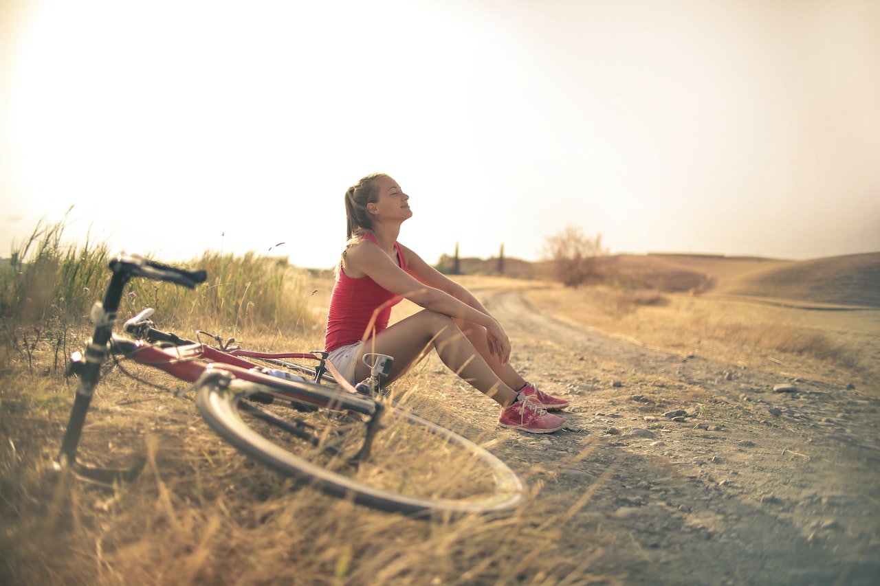 zittende vrouw met fiets in de zon